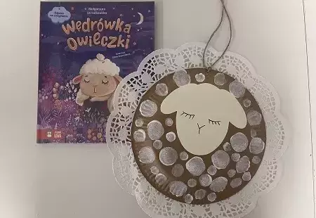 Zdjęcie książki pod tytułem Wędrówka owieczki oraz pracy plastycznej przedstawiającej owieczkę z papieru