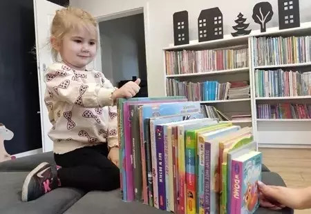 Dziewczynka z grupy Bibliomoliki trzymająca w dłoni szare zajączki wielkanocne wykonane z rolki po papierze.