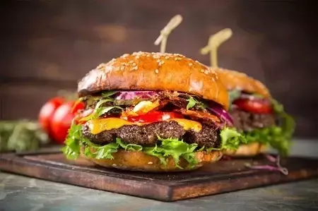 Zdjęcie przedstawiające dwa hamburgery leżące na stole