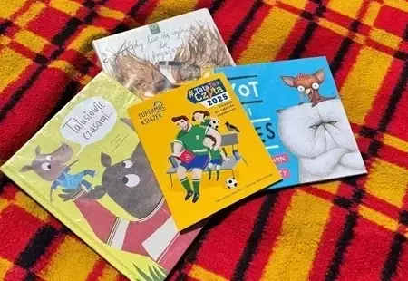 Cztery książki leżące na kolorowym kocu
