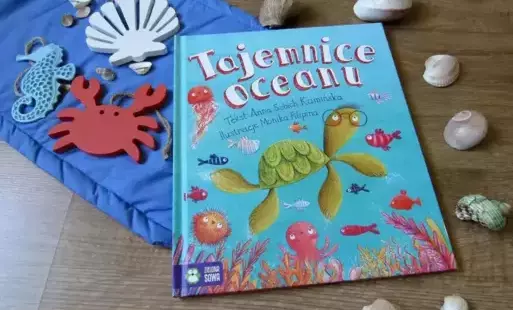 Okładka książki pt. Tajemnice Oceanu przedstawiająca zwierzęta zamieszkujące rafy koralowe zaprezentowana na tle morskich dekoracji.